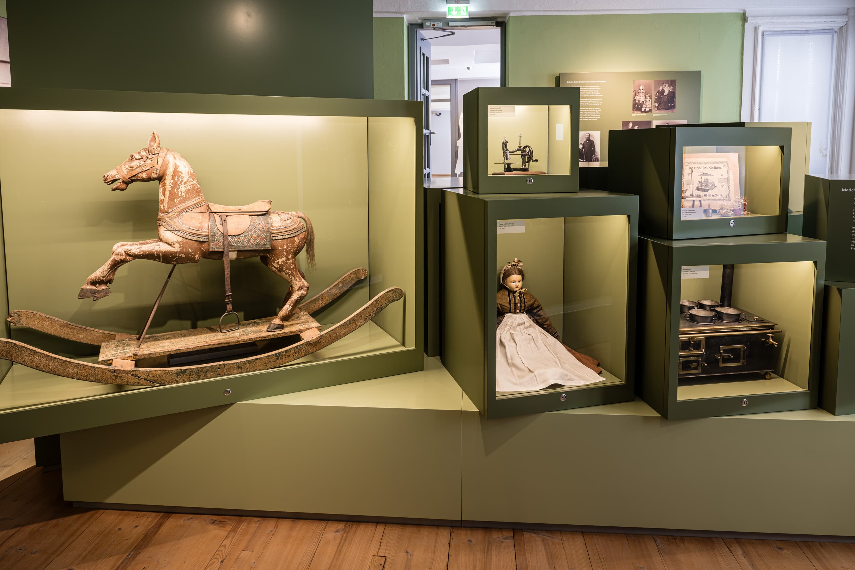 Ausstellung im Bomann-Museum: Altes Schaukelpferd aus Holz neben Puppe und Spielzeug-Herd.