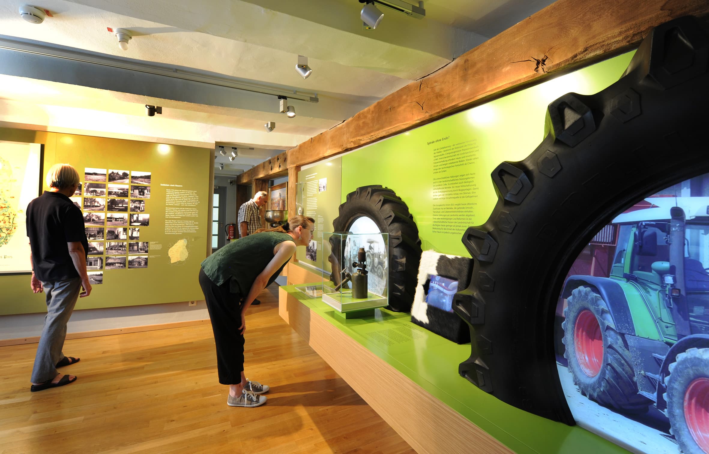 Blick in die Ausstellung 'Heide-Honig-Hightech' mit Besuchern vor einem Traktorreifen.