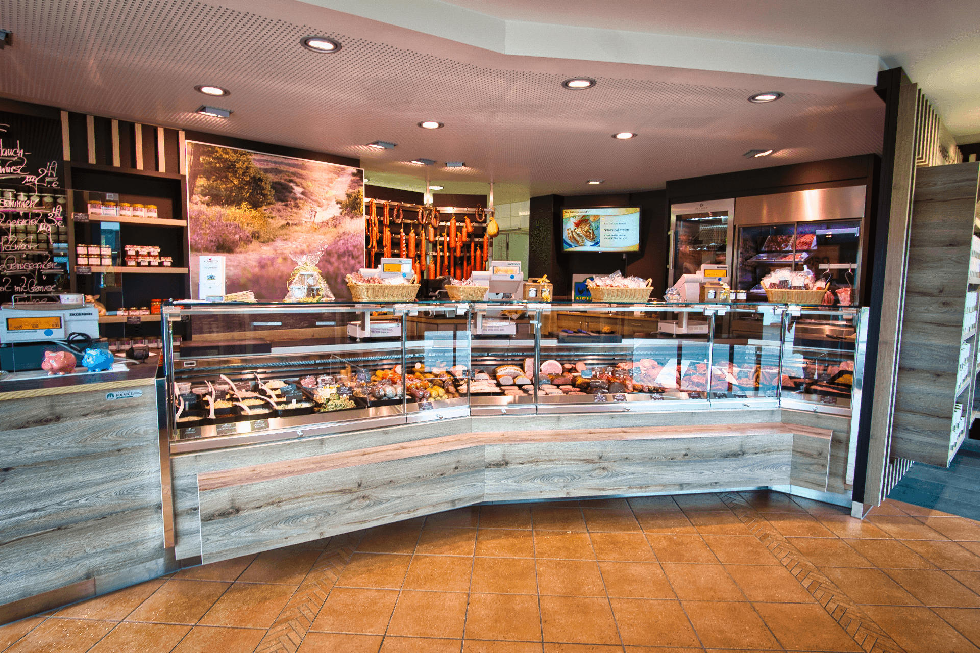 Helle Landschlachterei mit großer, reich gefüllter Glastheke für Fleisch- und Wurstwaren.