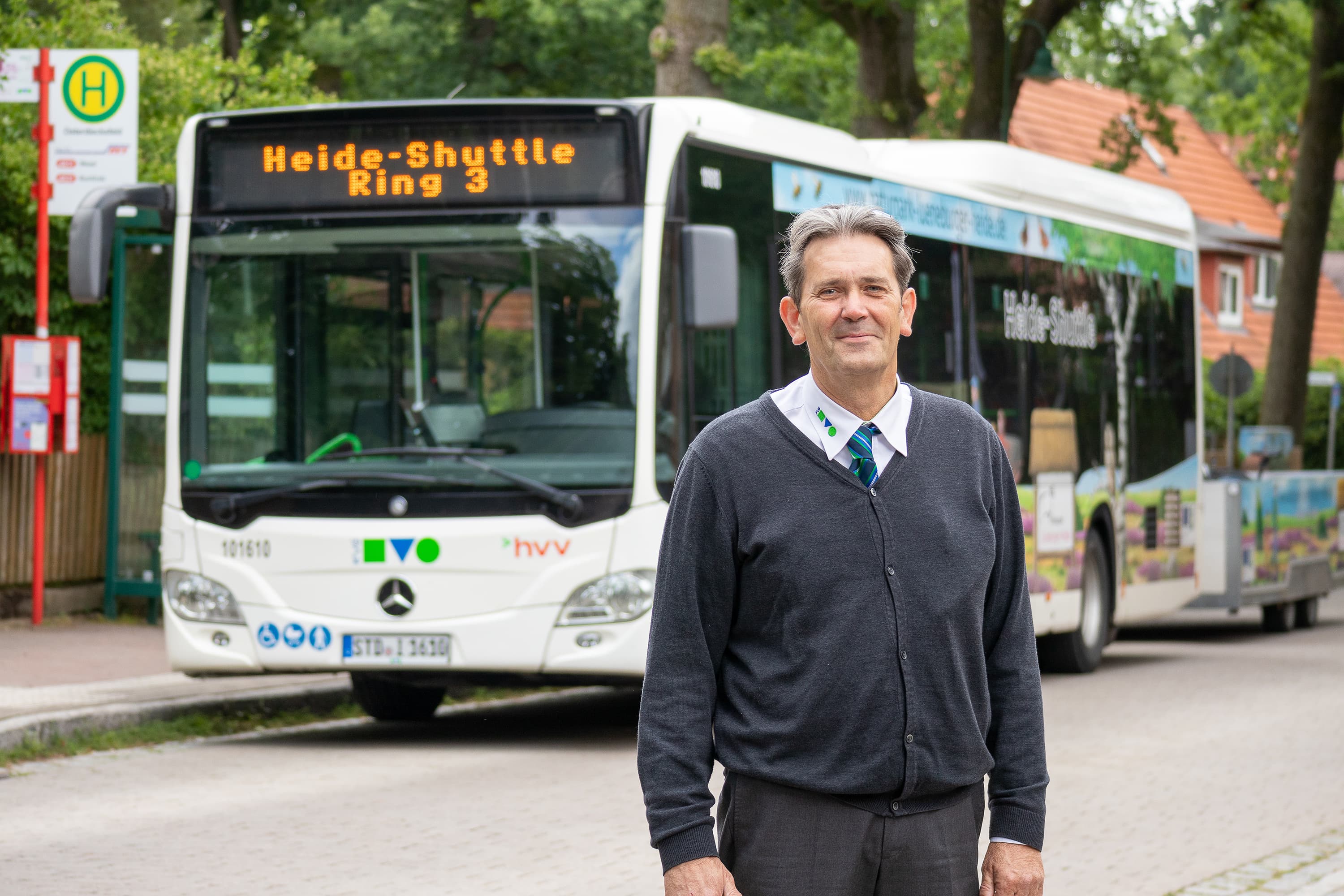 mann steht vor einem bus und lächelt