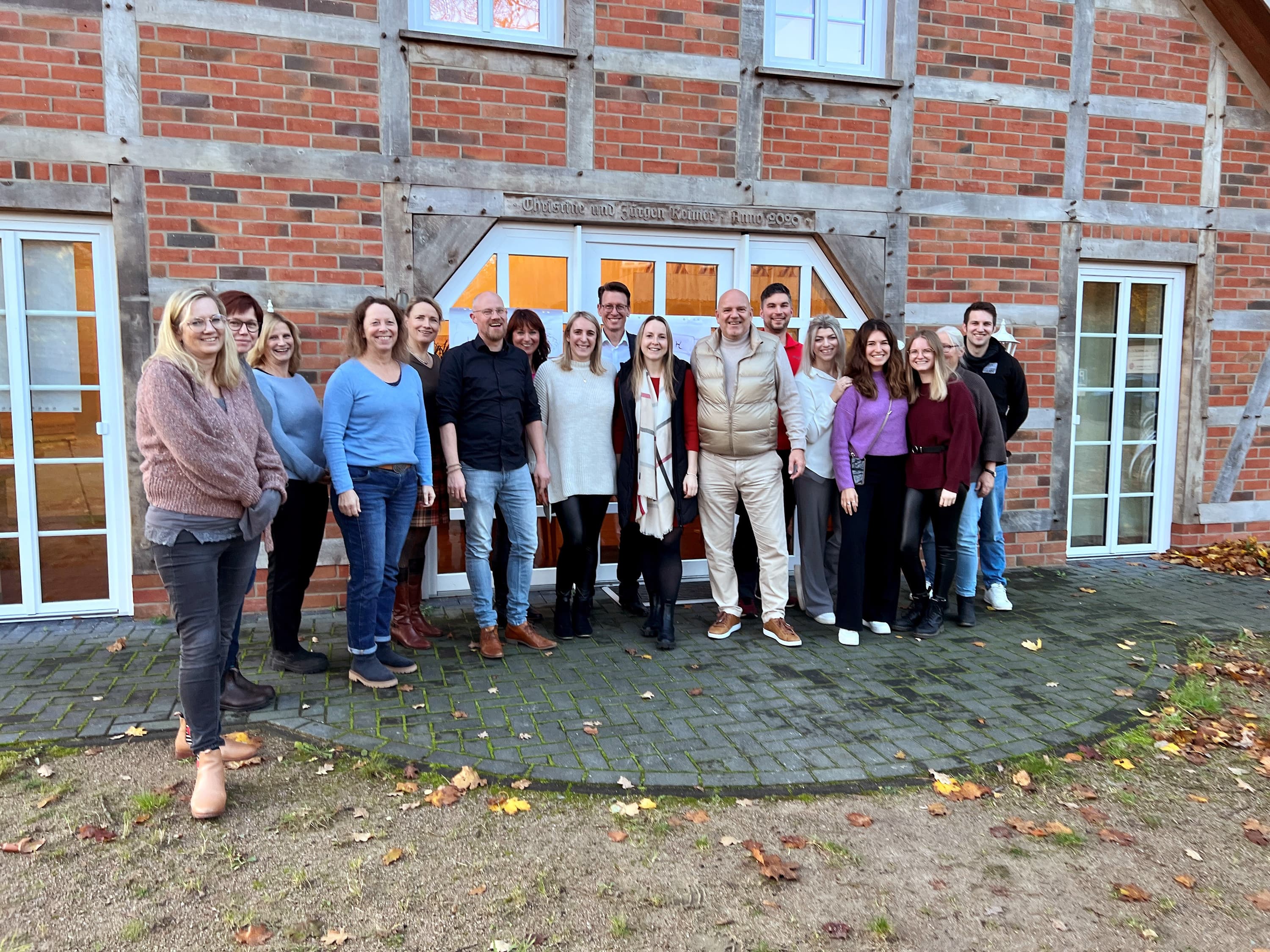 gruppe von jungen menschen steht vor einem haus und lacht