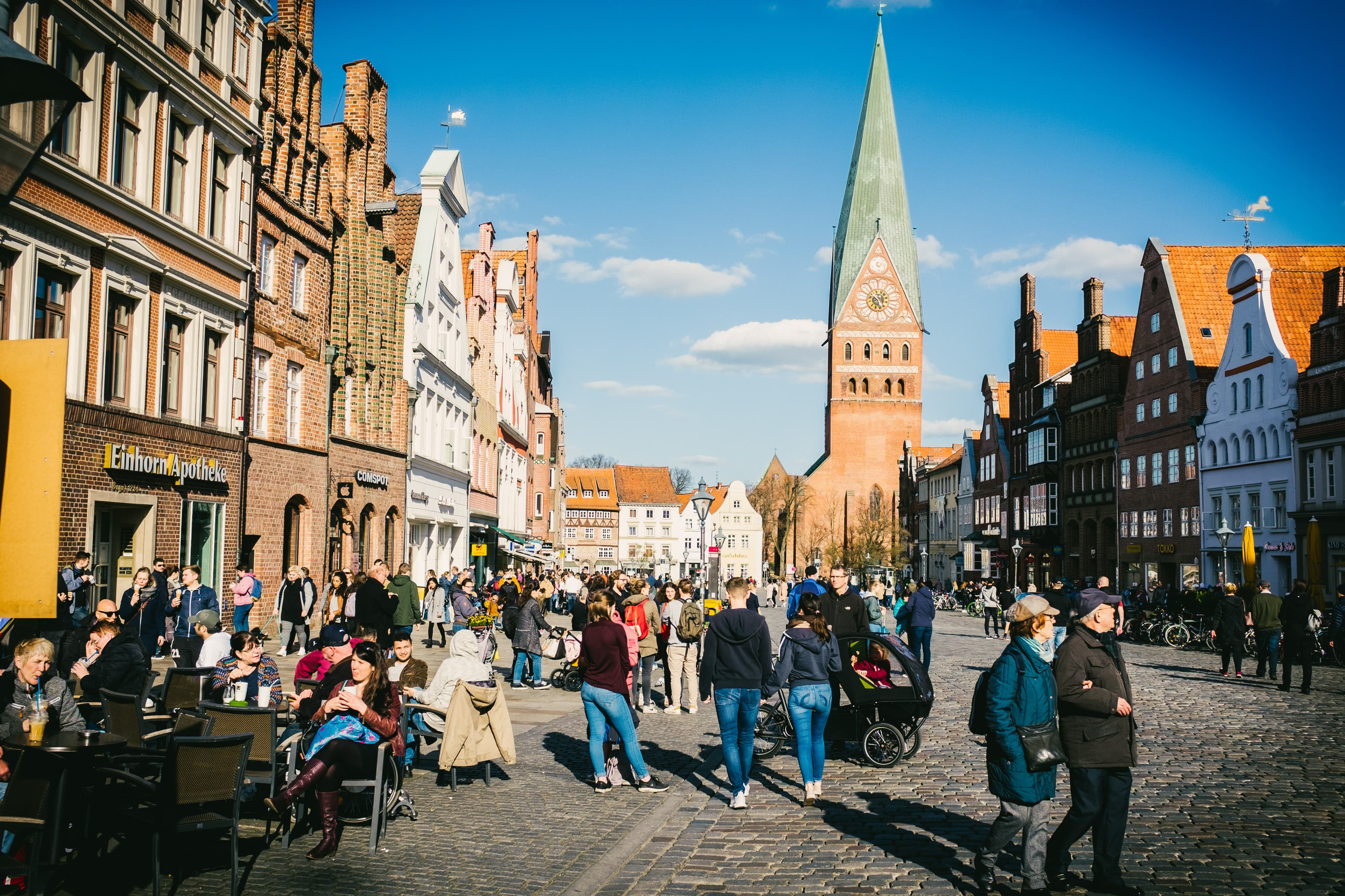 Viele Menschen flanieren an einem sonnigen Tag durch die historische Lüneburger Innenstadt.