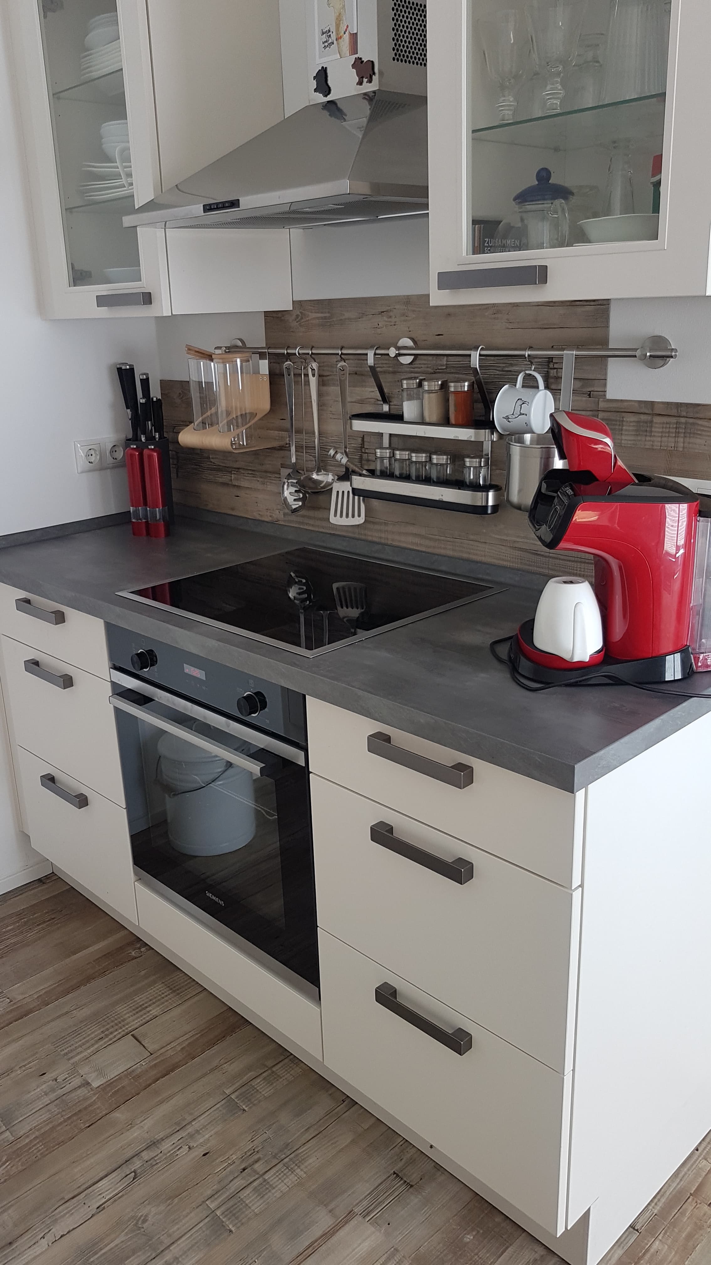 Moderne Küchenzeile mit Induktionsherd, roter Espressomaschine und hellem Holzdekor.