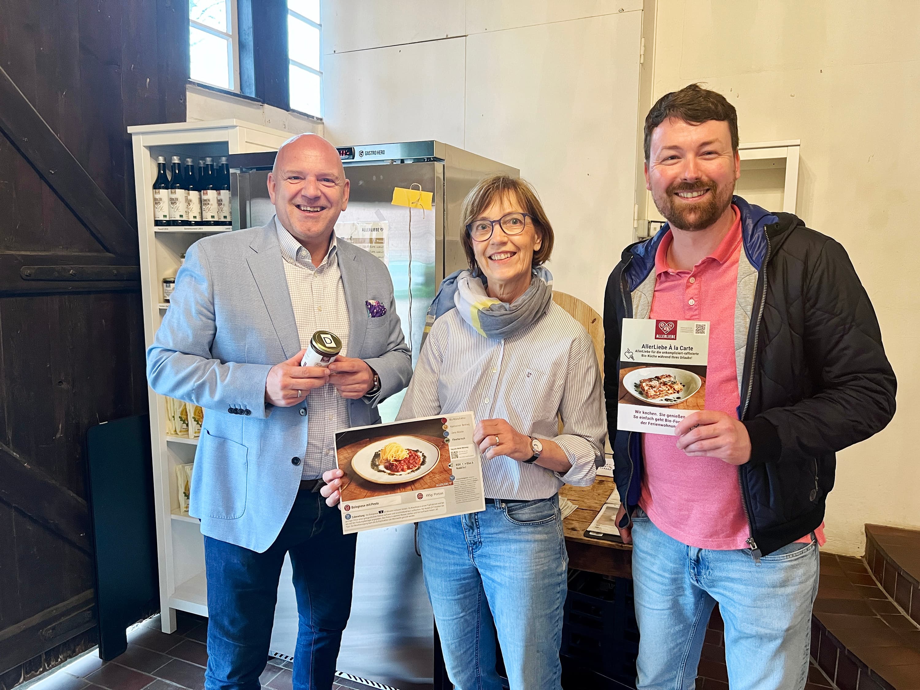 zwei Männer und eine Frau stehen vor einer Vitrine mit Essen