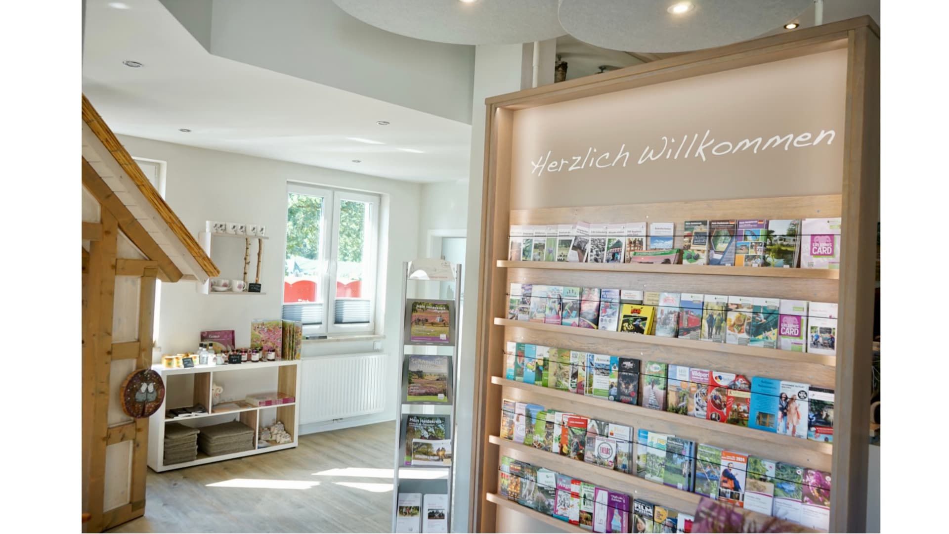 Tourist-Information im modernen Stil, mit Flyerregalen und "Herzlich Willkommen" Schriftzug.