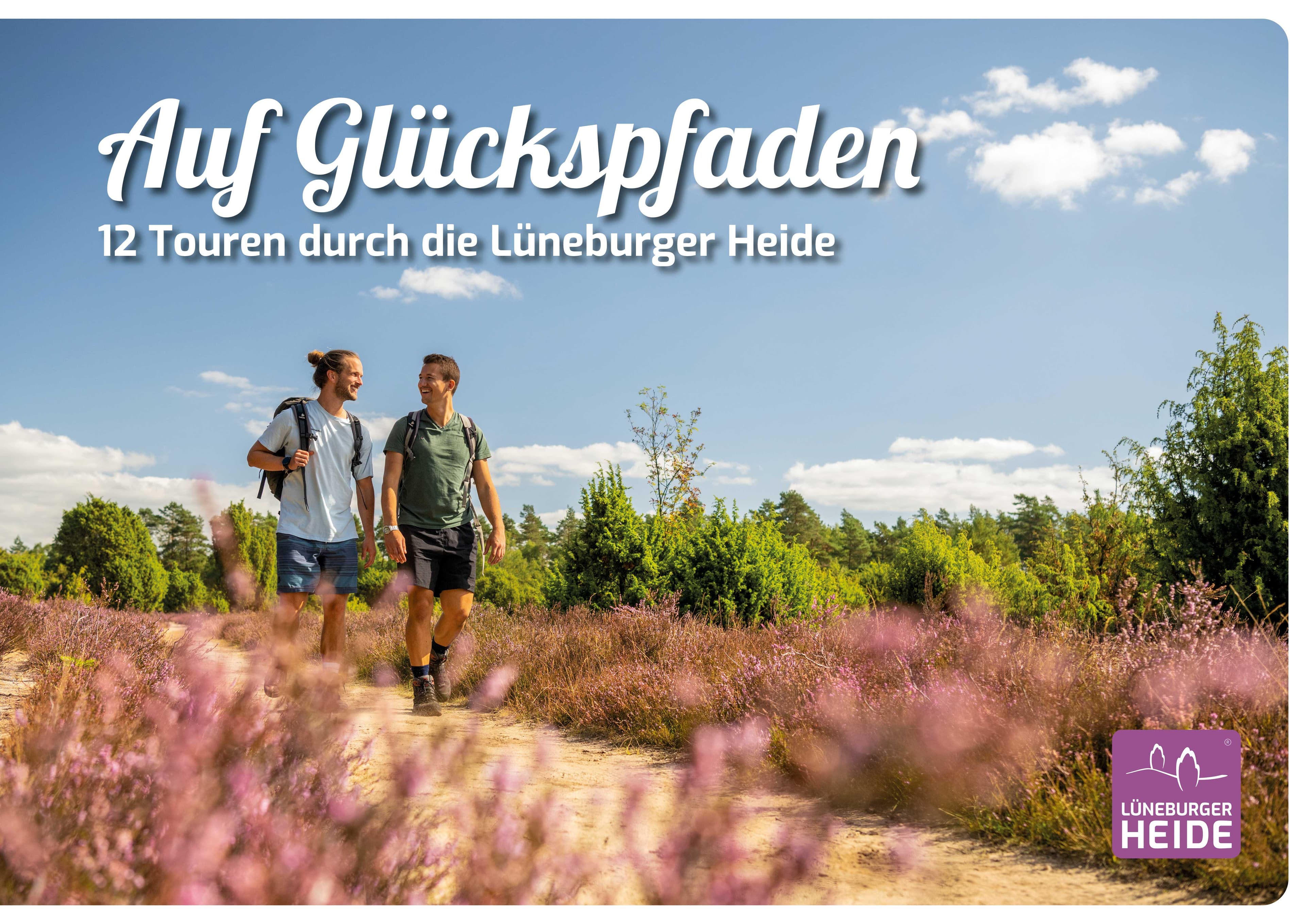 zwei männer wandern auf einem wanderweg durch die blühende lüneburger heide