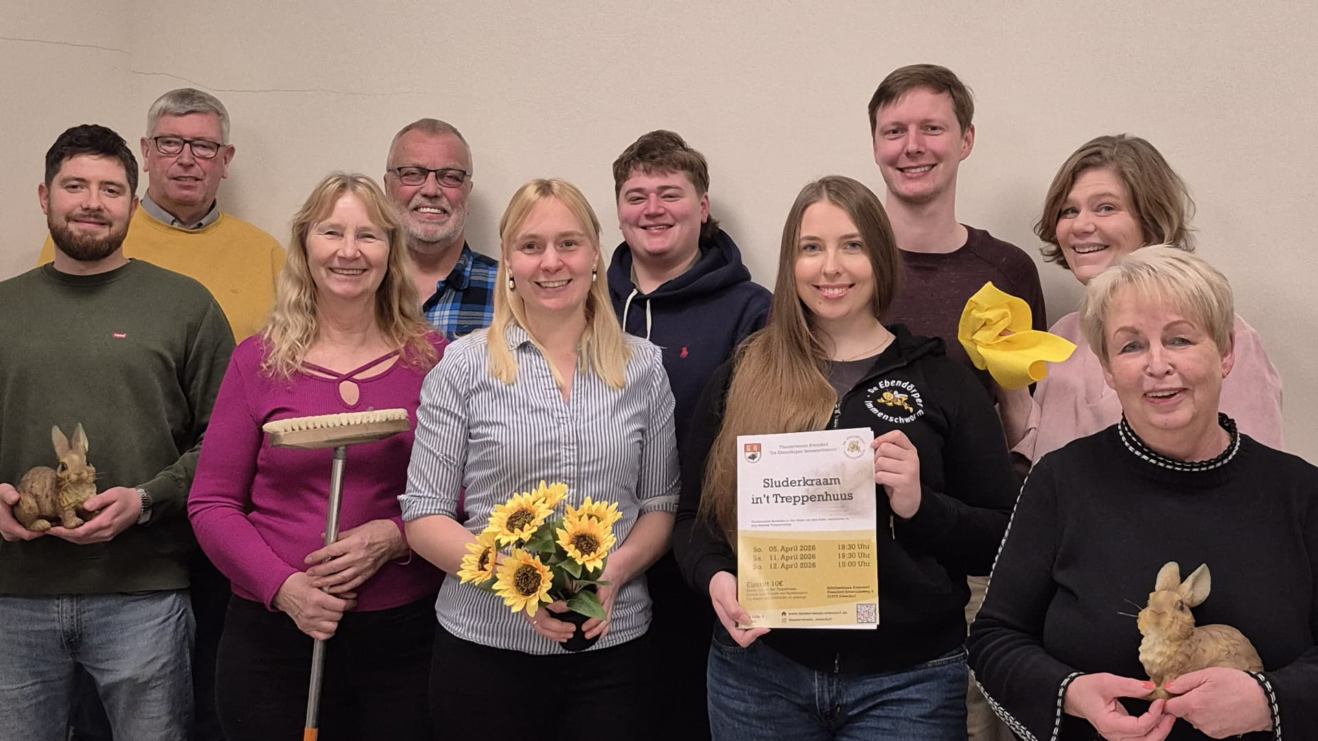 Zehn Personen der Theatergruppe Evendorf posieren mit Requisiten und einem Plakat.