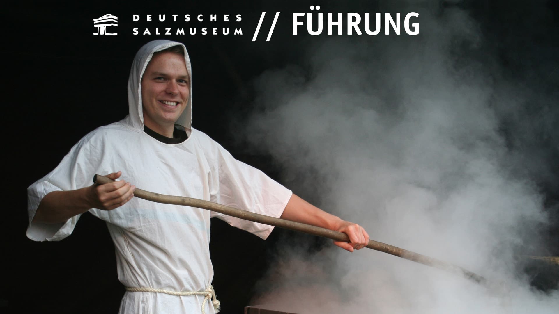 Ein Salzsieder mit weißer Kutte bei der Arbeit an einer dampfenden Siedepfanne.