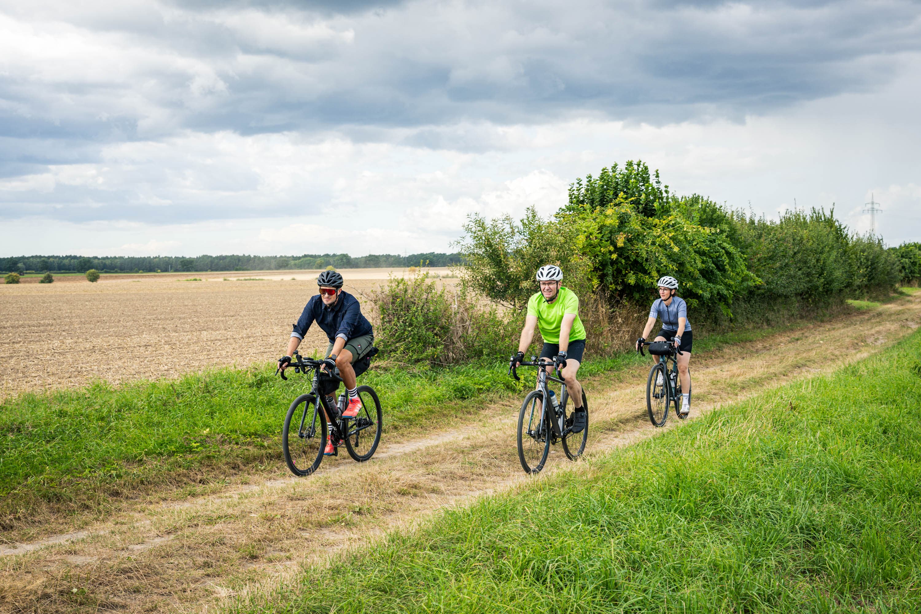 ein Feldweg in der Heideregion Uelzen mit 3 sportlichen Radfahrern auf ihren Gravelbikes