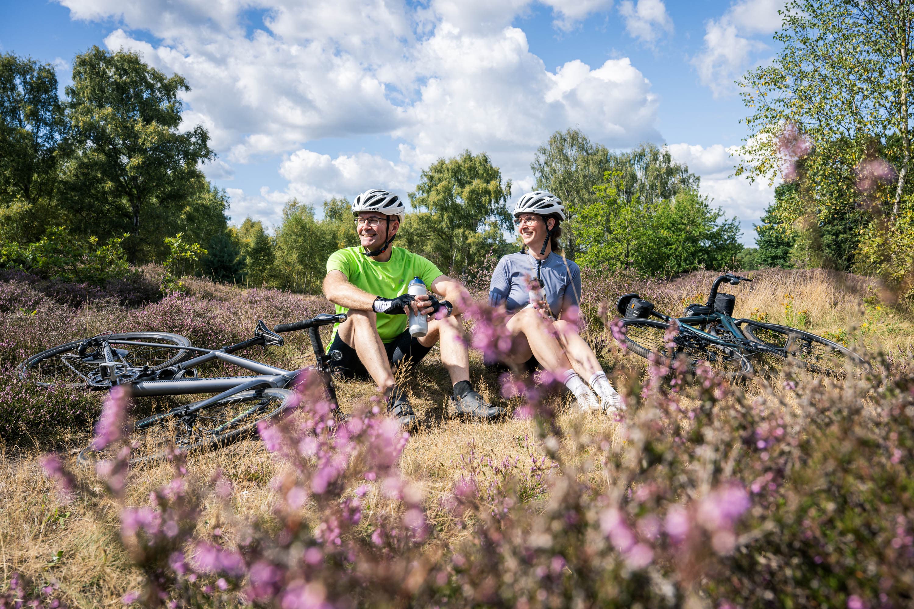 ein Pärchen mit Gravelbikes macht Rast auf ihrer Tour durch die blühende Heide