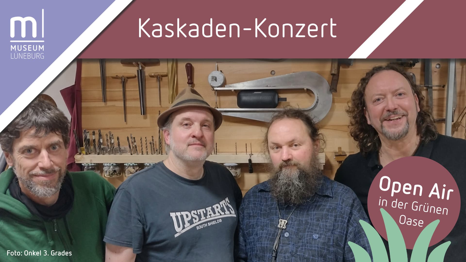 Vier Musiker vor einer Werkzeugwand in einer Werkstatt, Titel: Kaskaden-Konzert, Open Air in der Grünen Oase