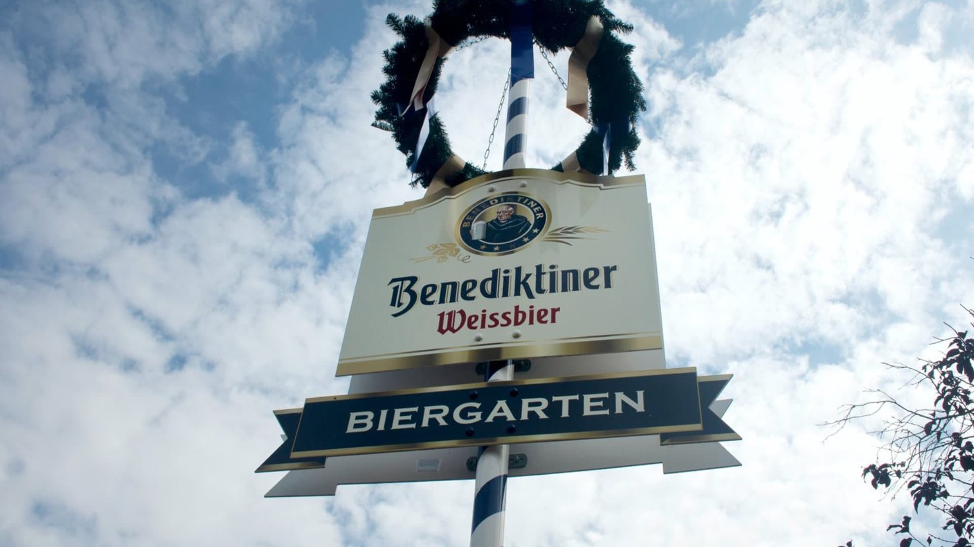 Mast mit Kranz, Schild für Benediktiner Weissbier und Wegweiser zum Biergarten.