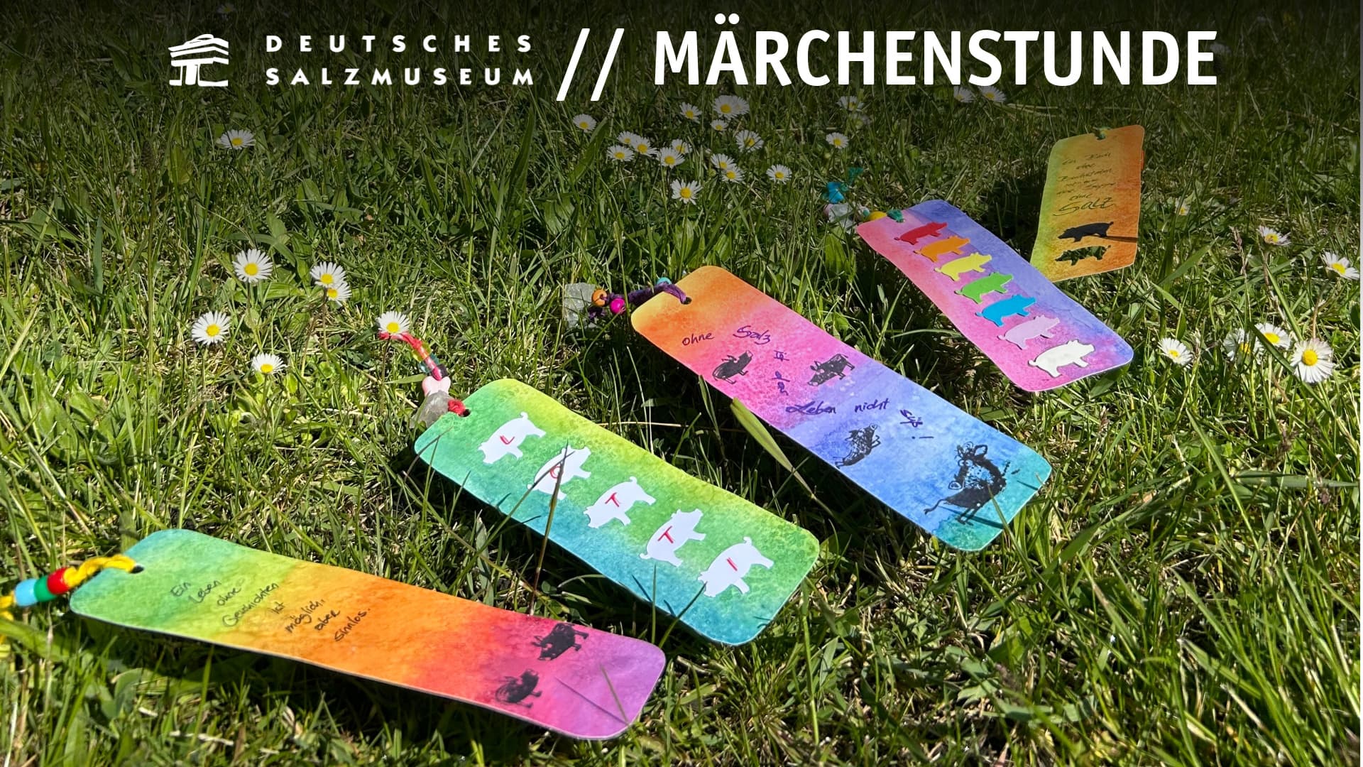 Bunte Lesezeichen mit Funkelkristallen und Salzsau-Motiven liegen auf einer Wiese