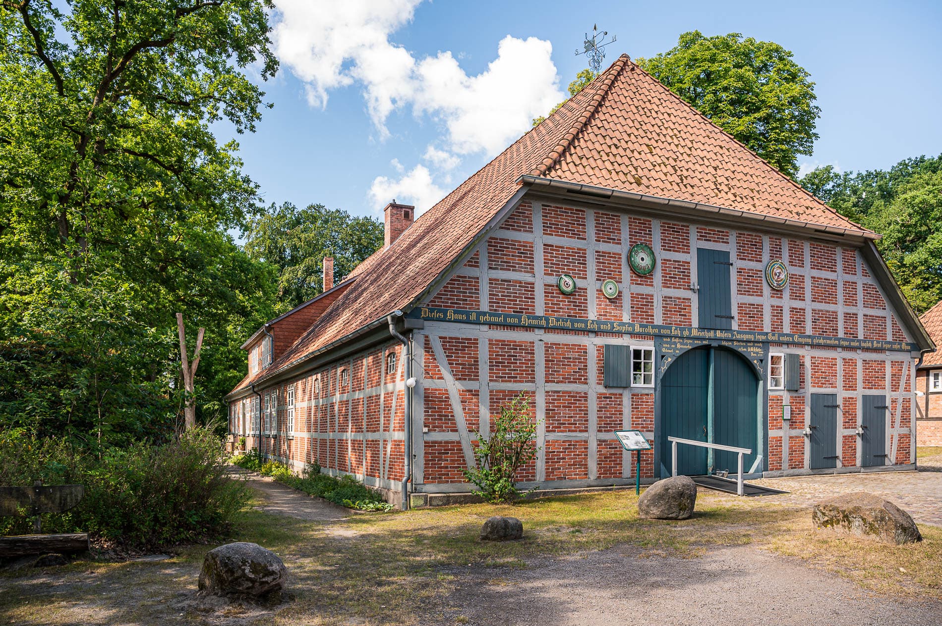 Das große Fachwerkhaus des Peetshofs in Wietzendorf umgeben von Bäumen an einem sonnigen Tag.