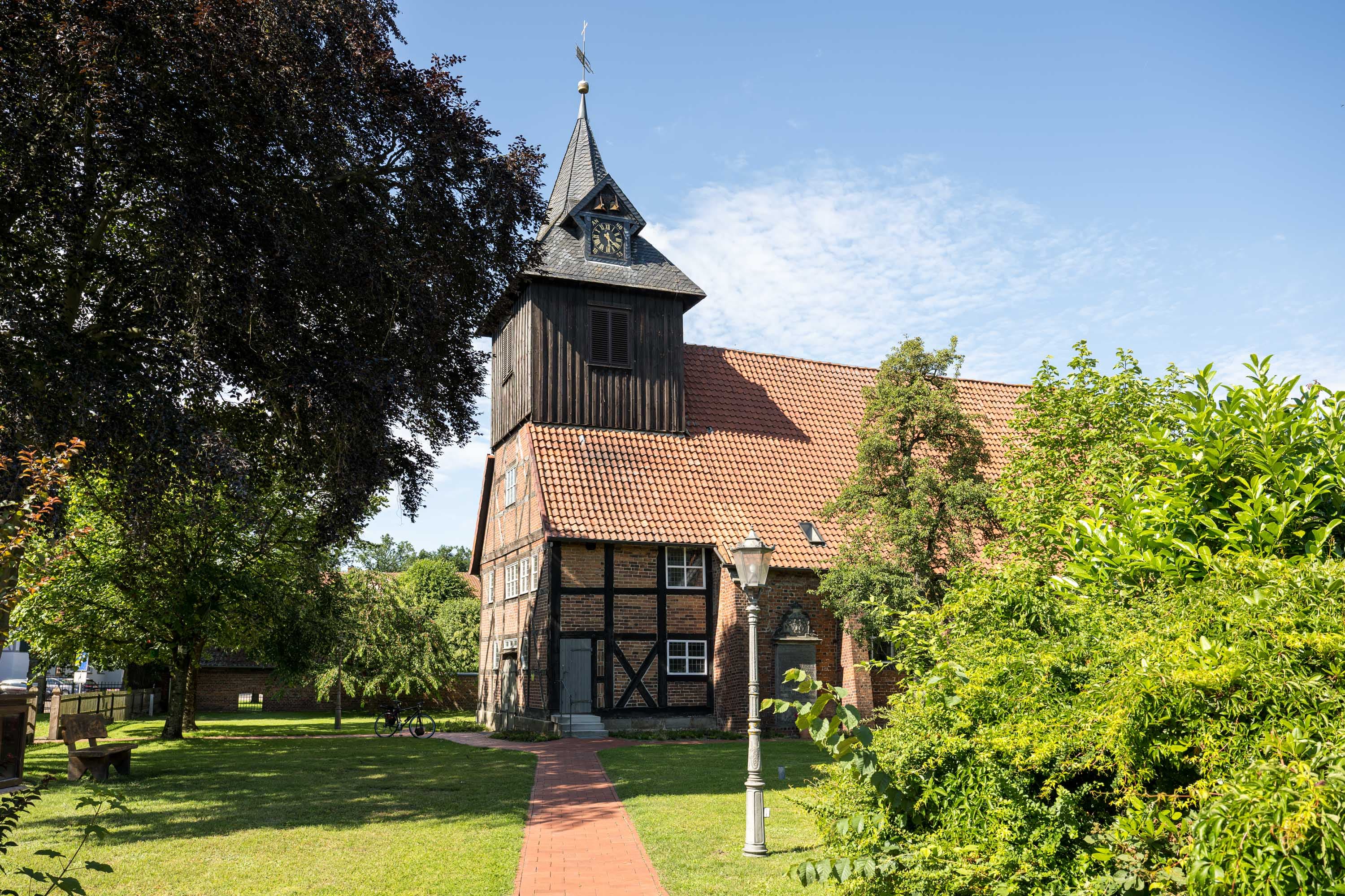 Johanniskirche mit Fachwerk, rotem Ziegeldach und Turm zwischen grünen Bäumen