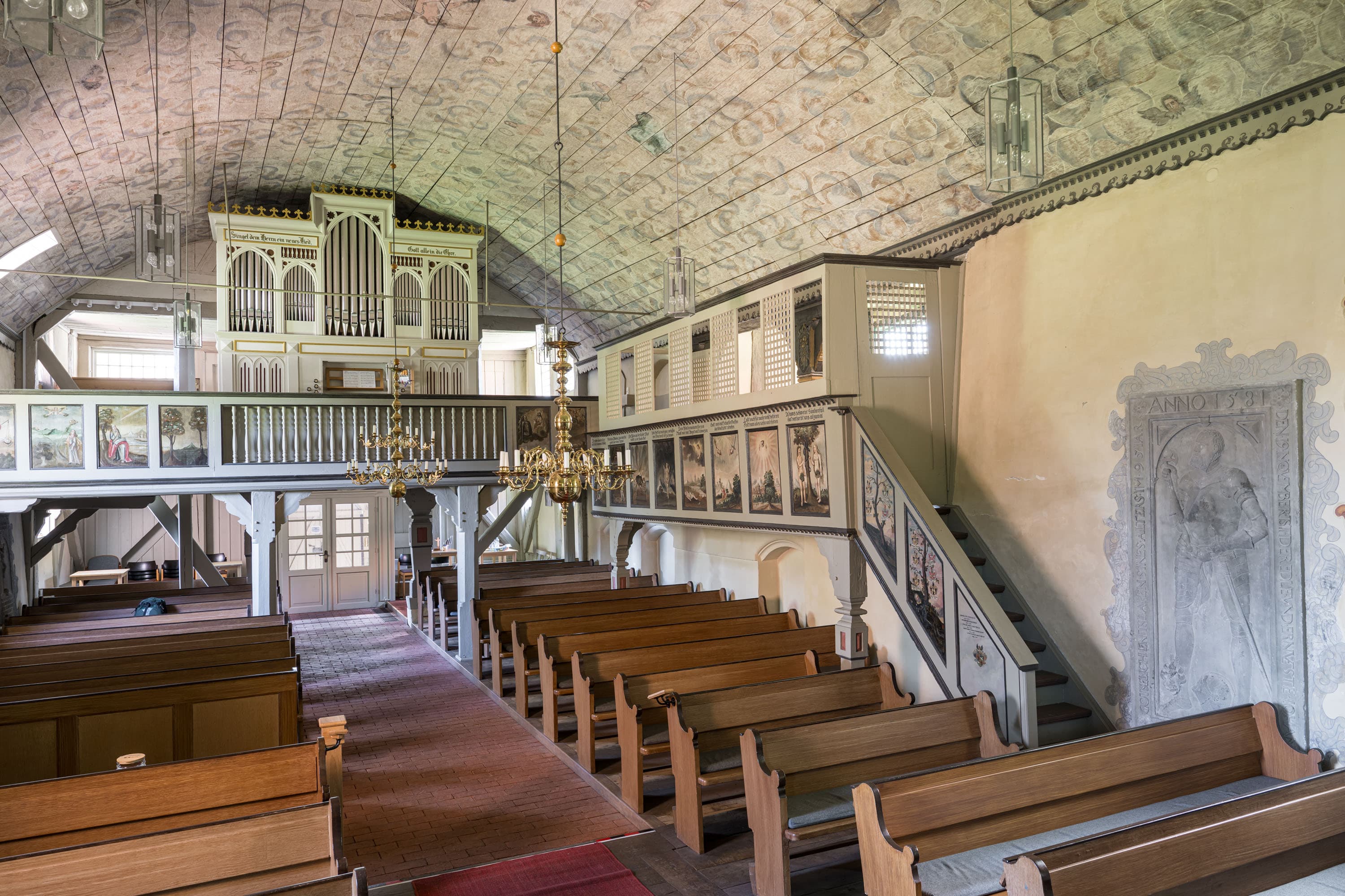 Innenraum der Johanniskirche mit Holzbänken, Orgelempore und bemalter Gewölbedecke