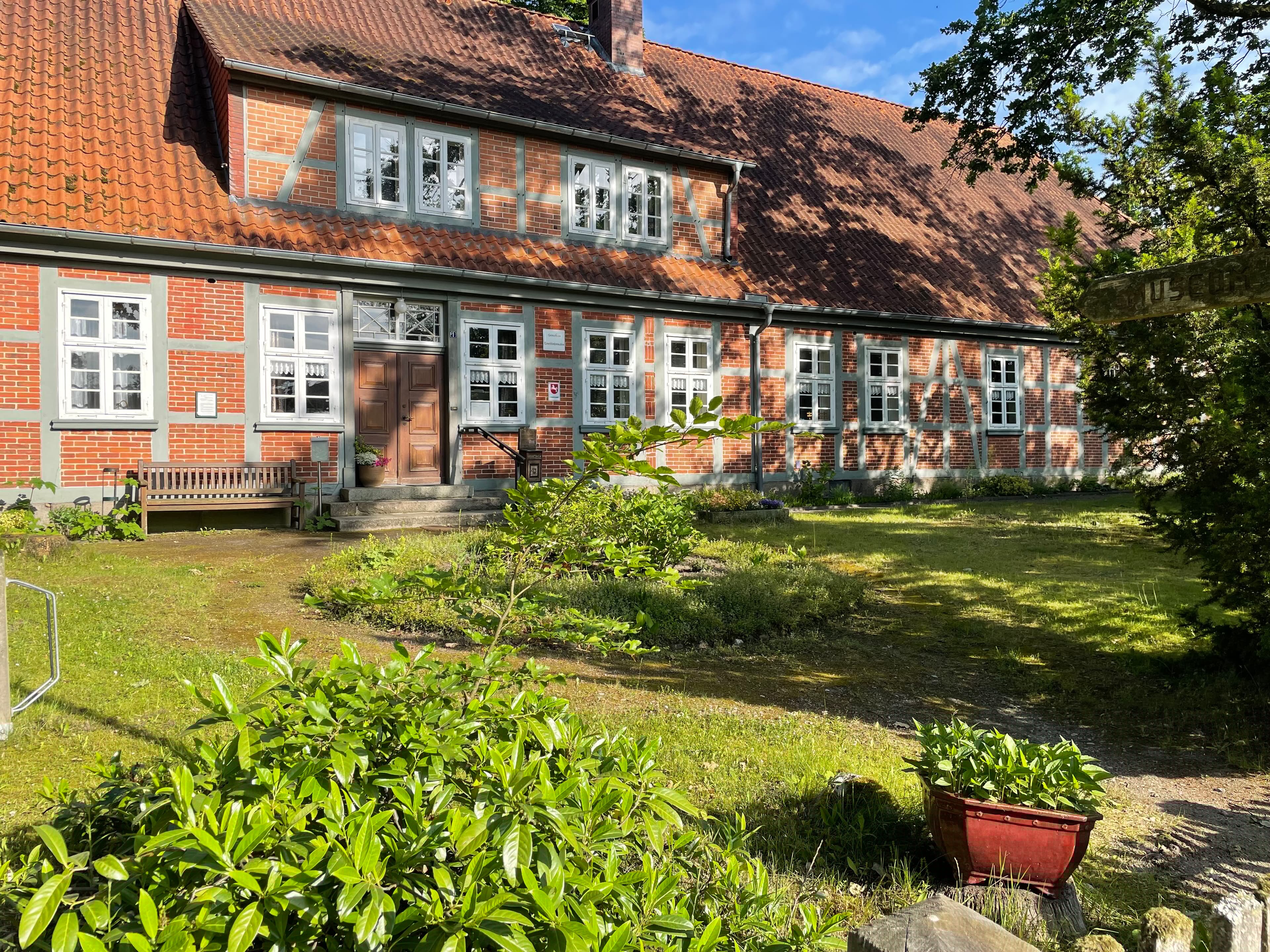 Das Hauptgebäude des Peetshofs, ein historisches Fachwerkhaus mit Garten im Sonnenlicht.