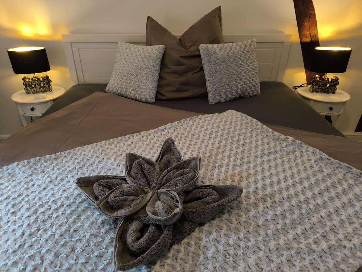 Doppelbett mit beiger Strickdecke, Kissen und Handtuchblume im Löwenzimmer