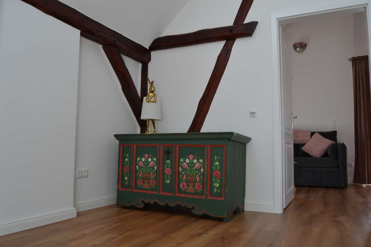 Flur im Obergeschoss mit bemaltem Bauernschrank und Blick ins Wohnzimmer