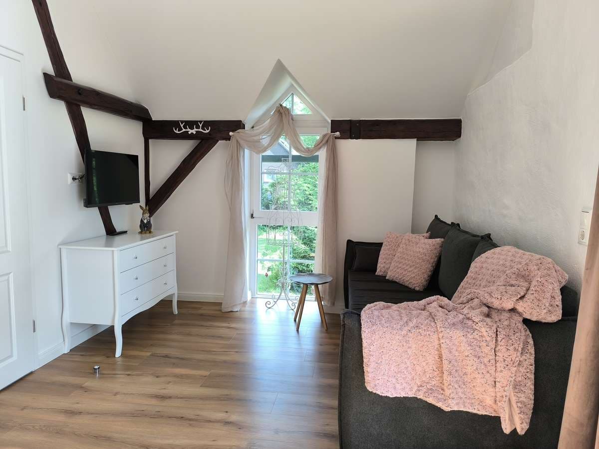Sitzecke im Balkonzimmer mit dunklem Schlafsofa (160x200cm), Fernseher und Giebelfenster