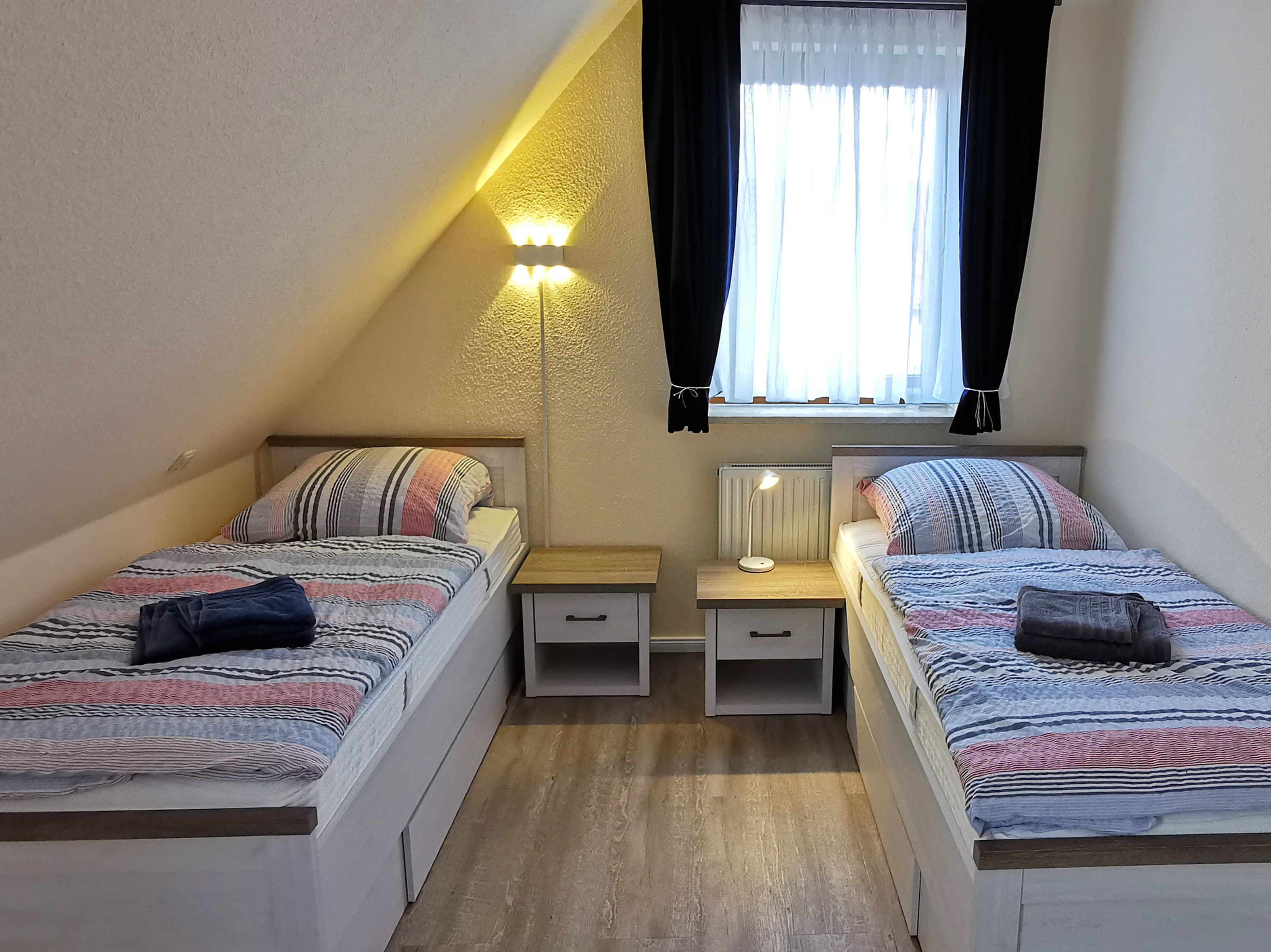 Ein gemütliches Schlafzimmer mit zwei Einzelbetten. Das Zimmer hat eine helle Fensterfront und moderne Möbel.