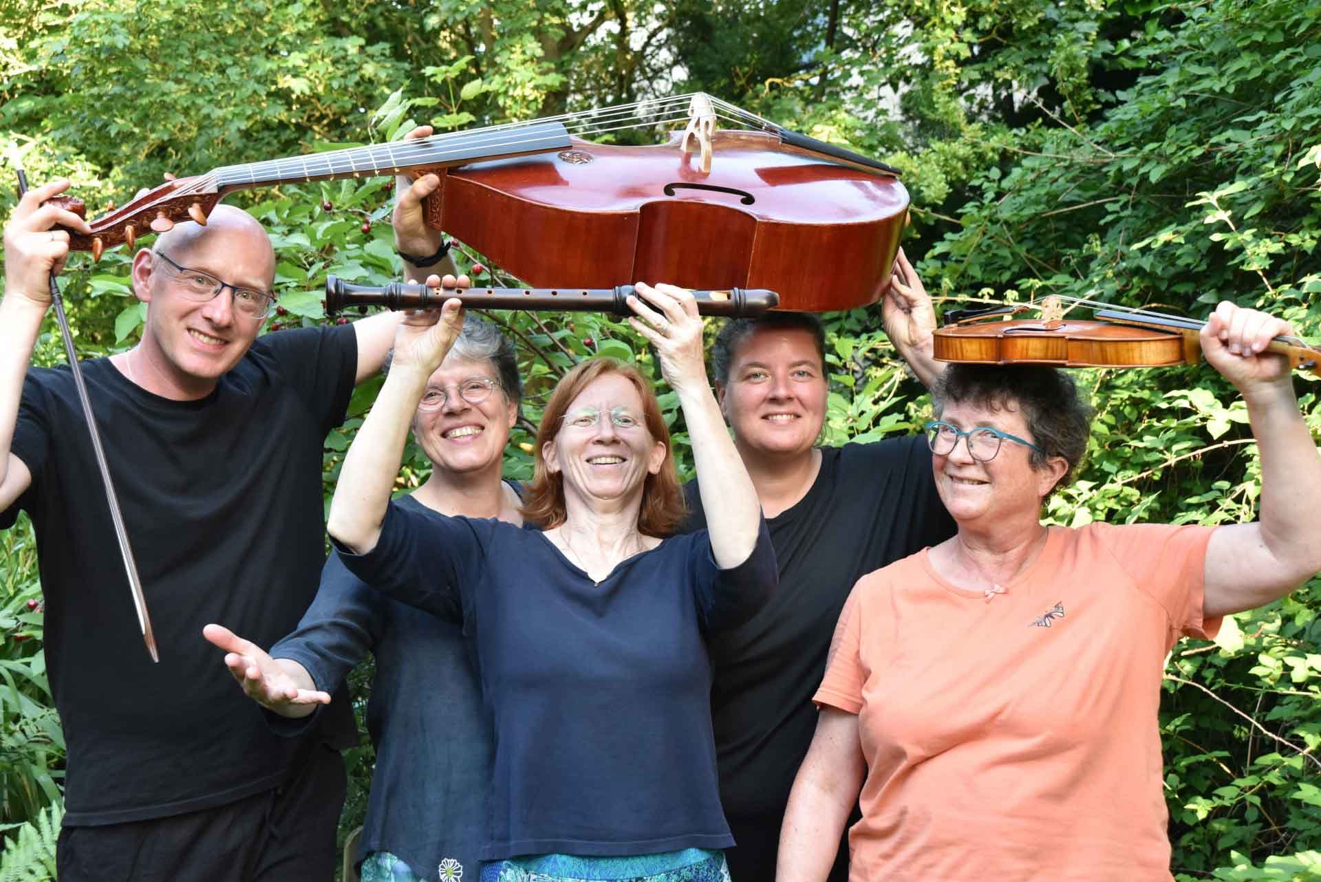Fünf Ensemblemitglieder halten Streichinstrumente und Flöte vor dichtem Laub.