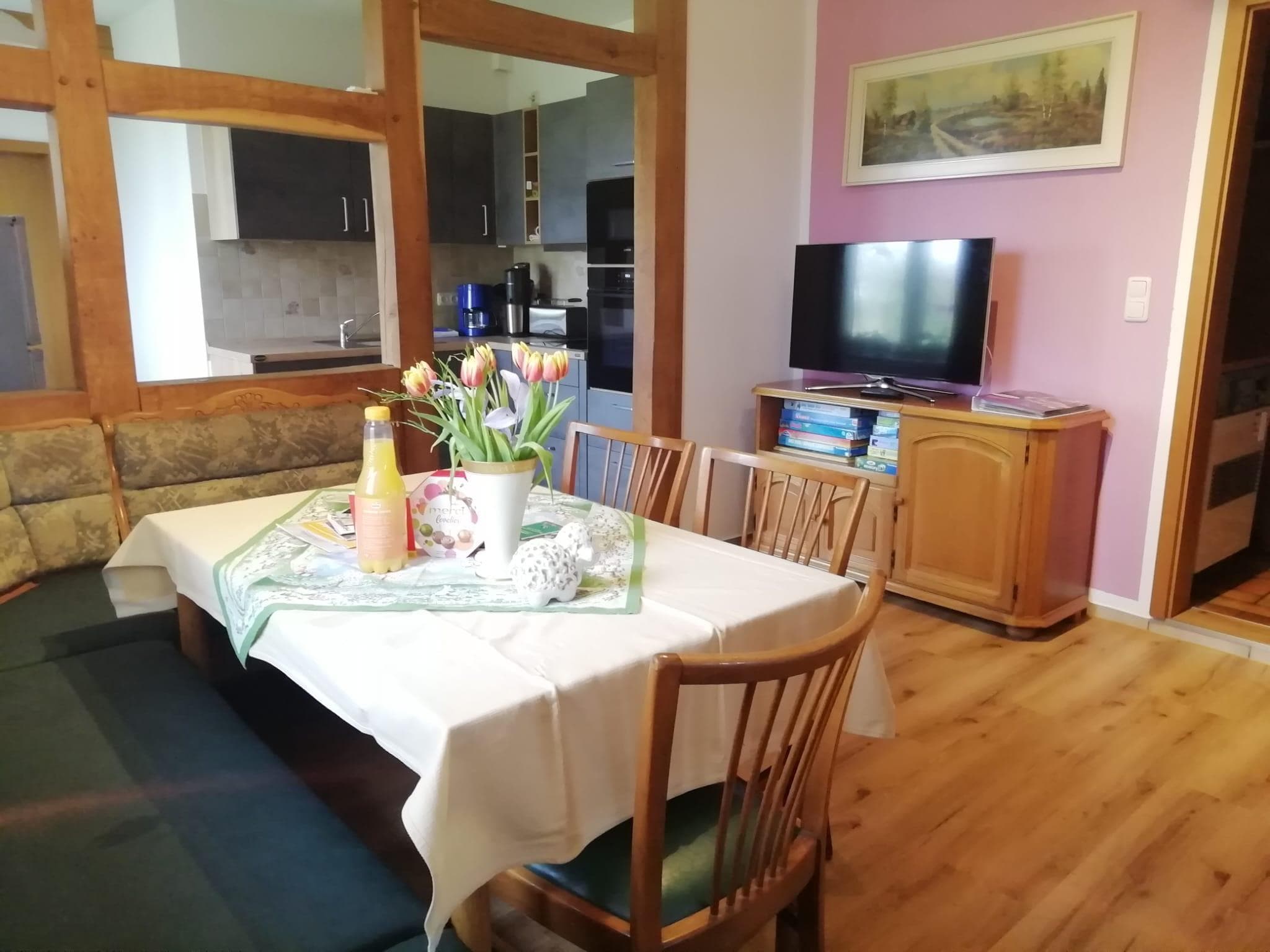 Wohnküche mit Esstisch, Eckbank, Küchenzeile und TV-Schrank in einer Ferienwohnung.