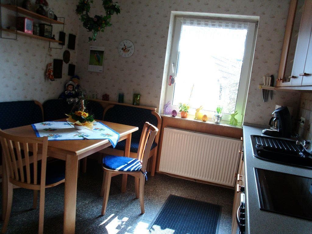 Küche mit Essecke, Holztisch, Eckbank, Stühlen, Fenster und Arbeitszeile.