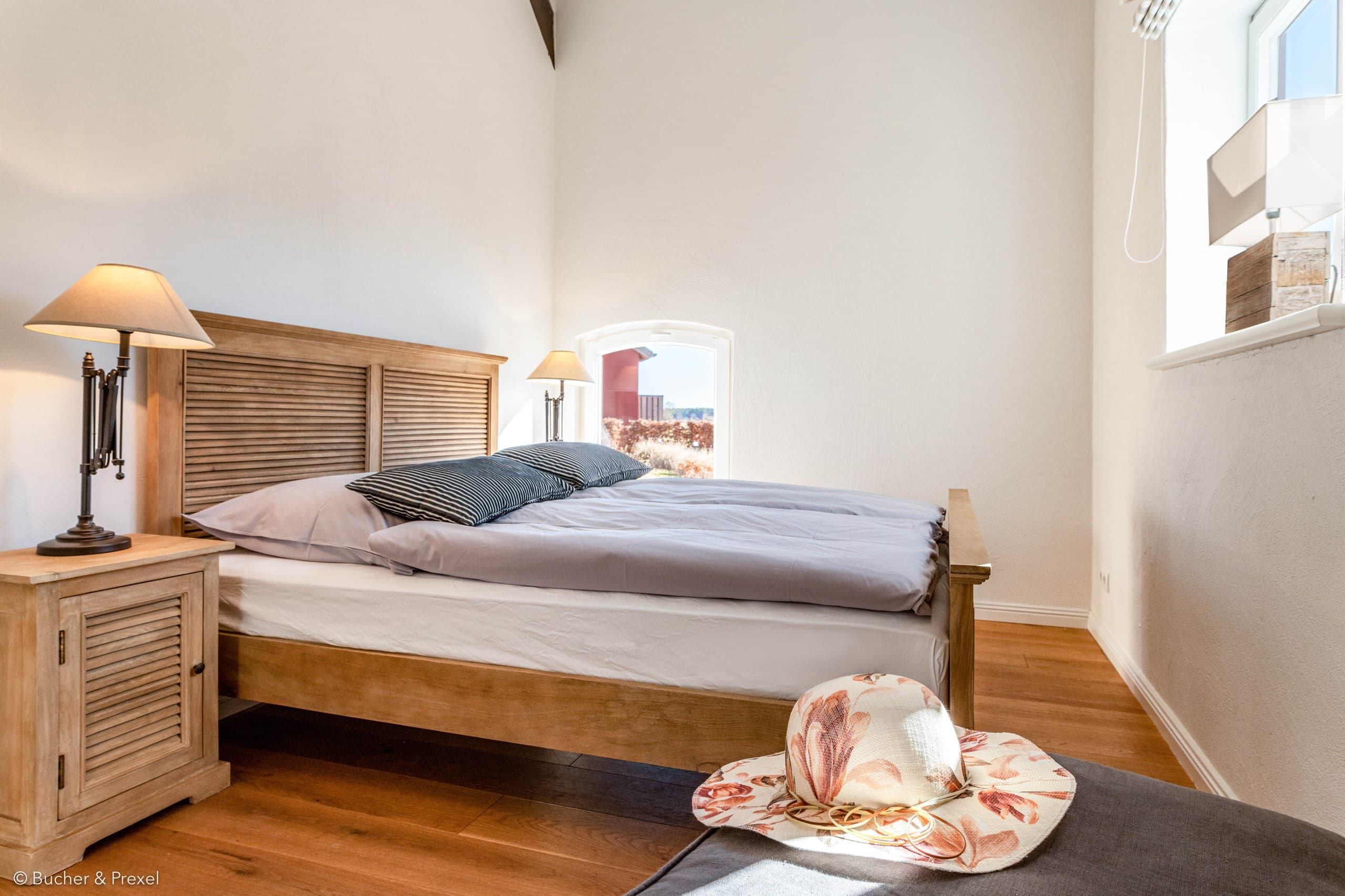 Schlafzimmer mit Doppelbett aus Holz und Nachttischlampen in Apartment I