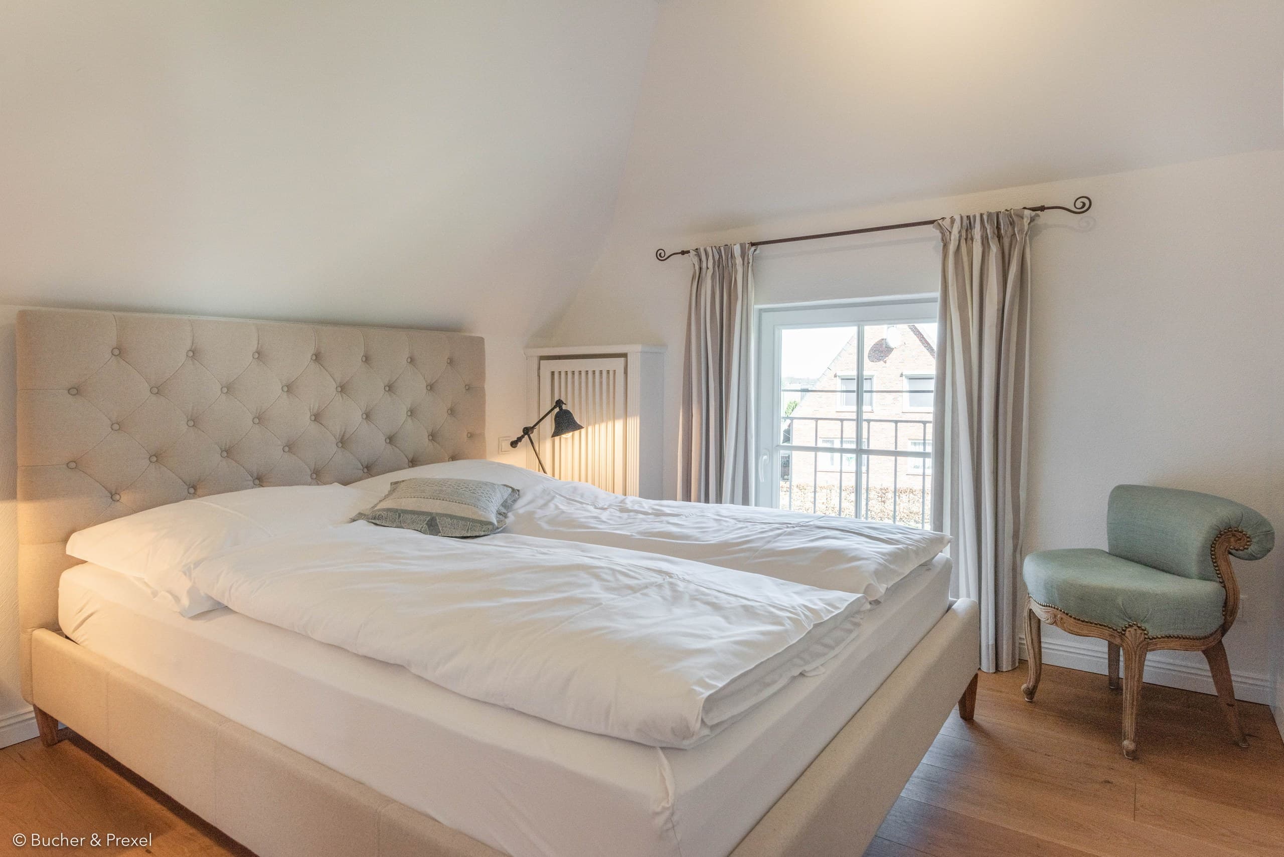 Helles Schlafzimmer mit Polsterbett unter der Dachschräge in Apartment IV