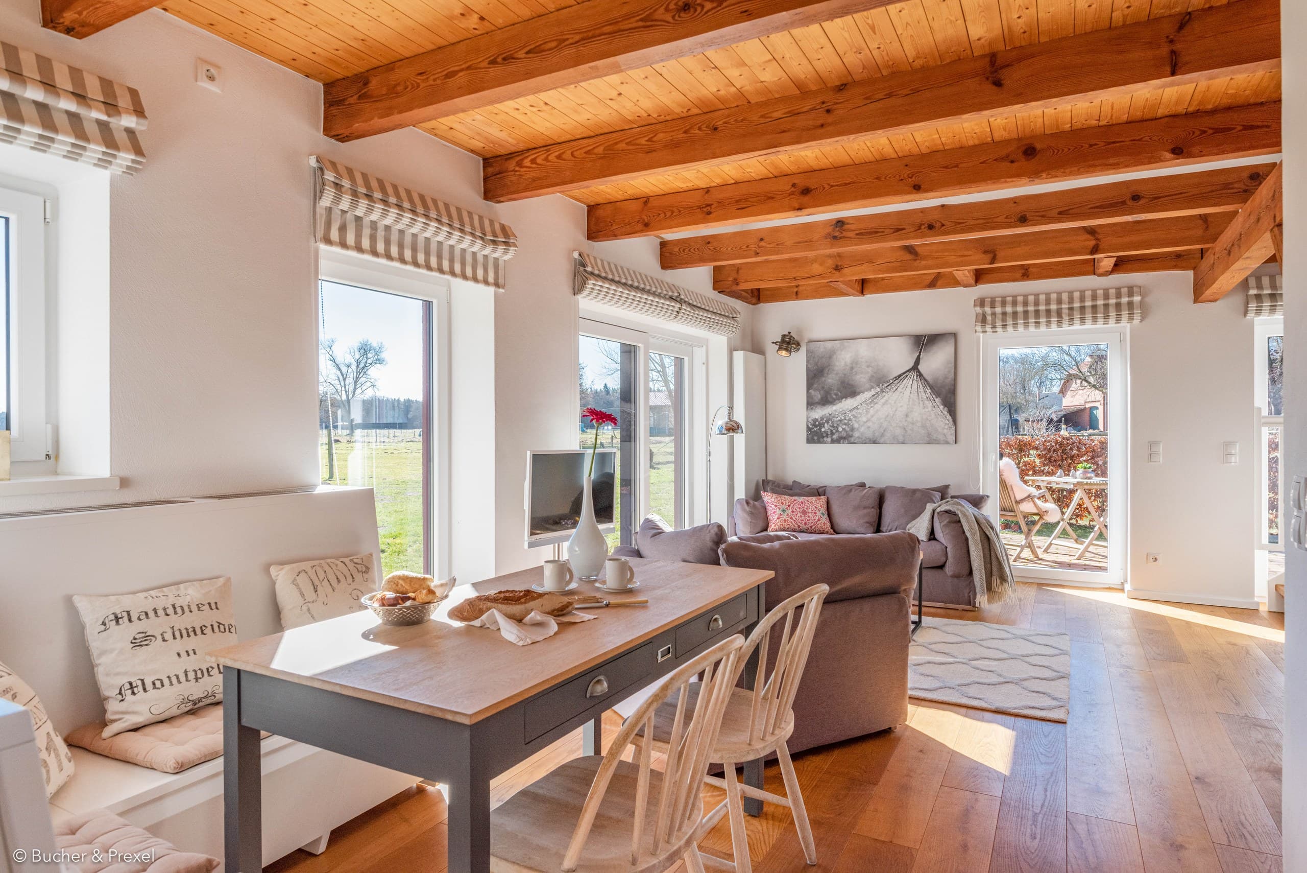 Offener Wohn- und Essbereich mit Holzbalkendecke, Sofa und Tür zur Terrasse in Apartment VII