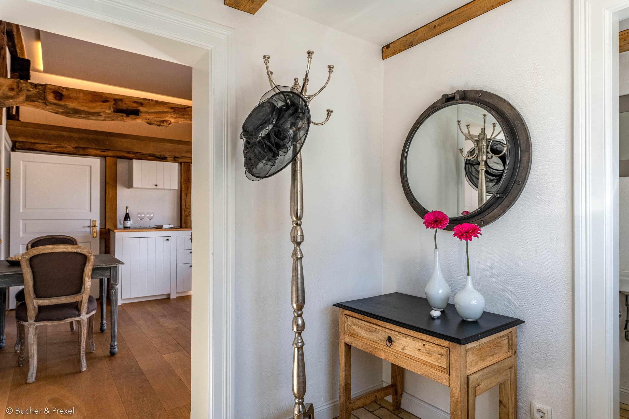 Eingangsbereich mit Garderobe und rundem Spiegel, Blick in die Küche von Apartment VI