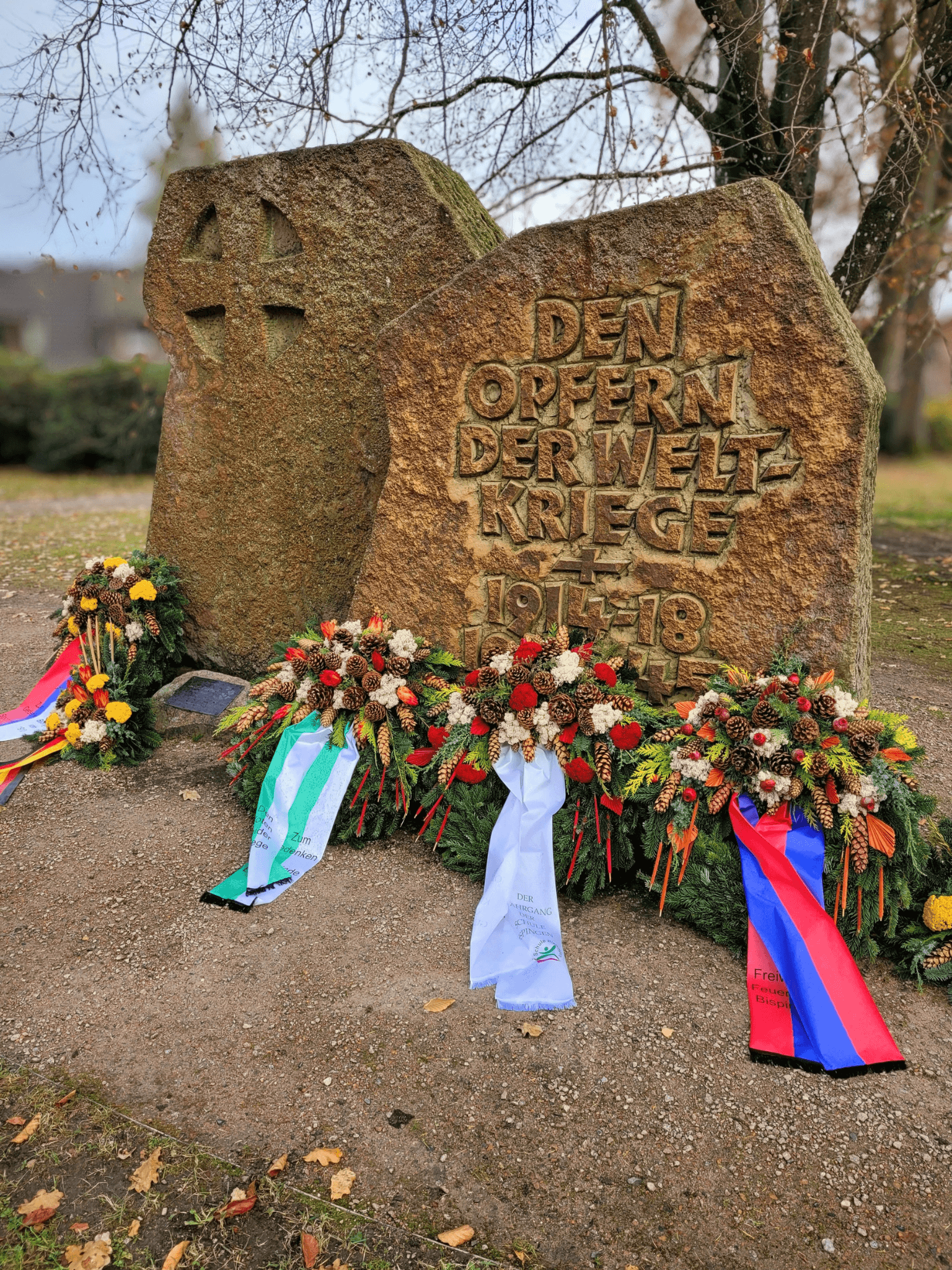Gedenkstein für die Opfer der Weltkriege mit Kränzen und Schleifen in Bispingen.