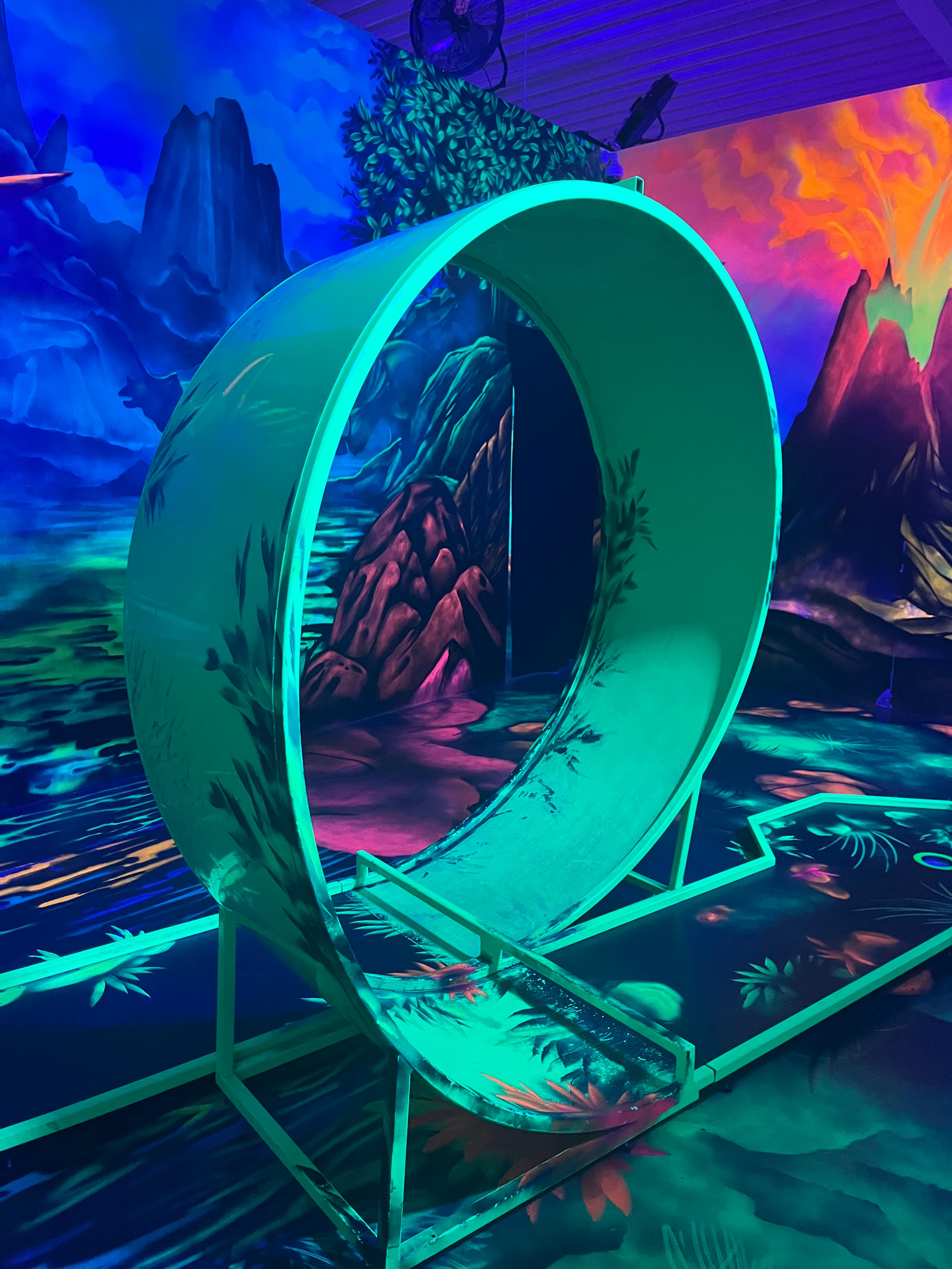 Neonfarbenes Schwarzlicht-Minigolf mit Looping und fantasievoller Felslandschaft.
