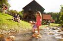 Eine Familie amüsiert sich am Wasser vor dem Bauernhof
